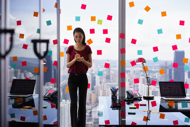 Busy Person Writing Many Sticky Notes On Large Window